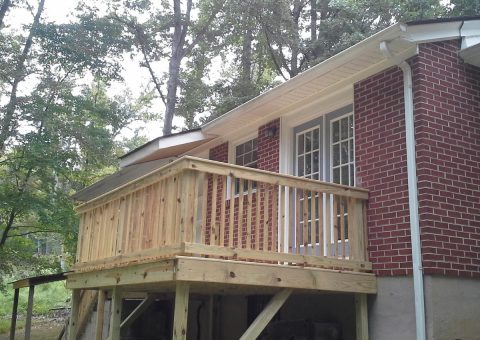 A house with a bricks sidewall and a wood deck