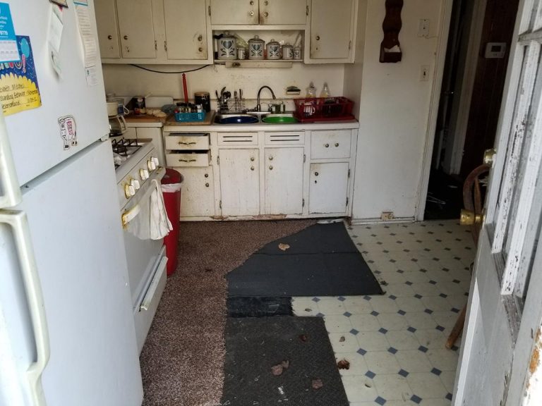 Dirty old kitchen with rust all over the kitchen cabinets and old floormat