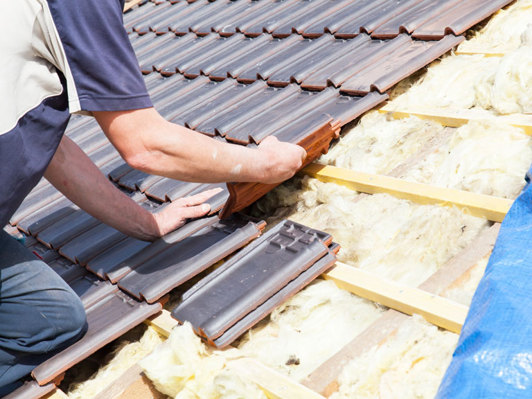 A Triad roofing contractor installing asphalt shingles on the rooftop