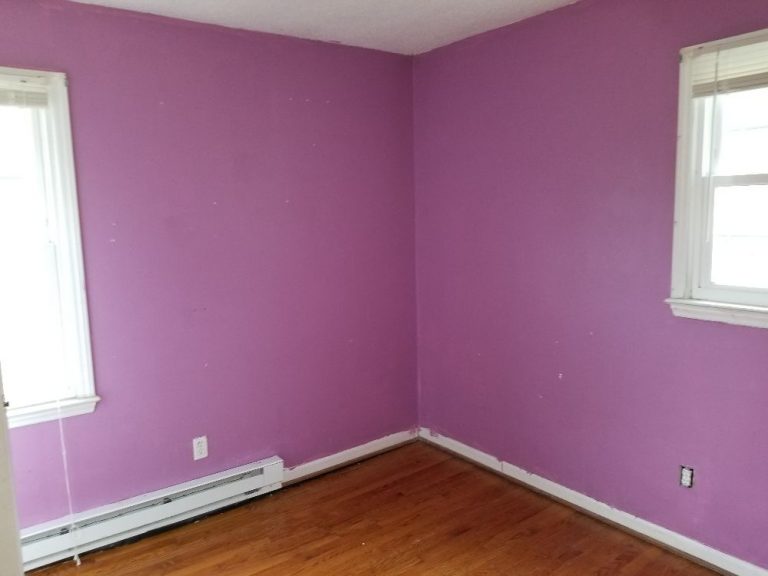 A room with a pink wall and a hardwood flooring